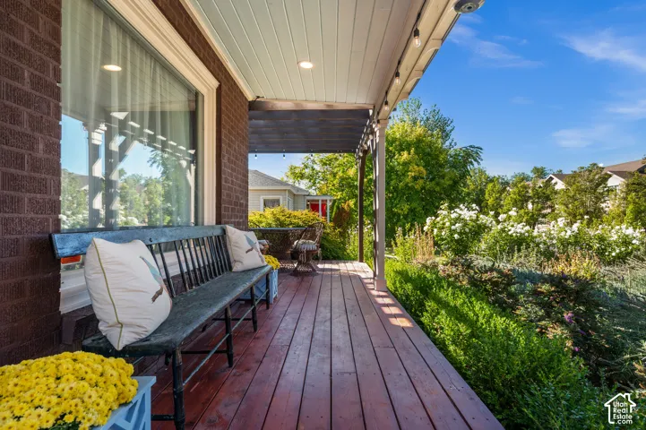 Covered porch with wood-finish decking, recessed lighting, and brick exterior