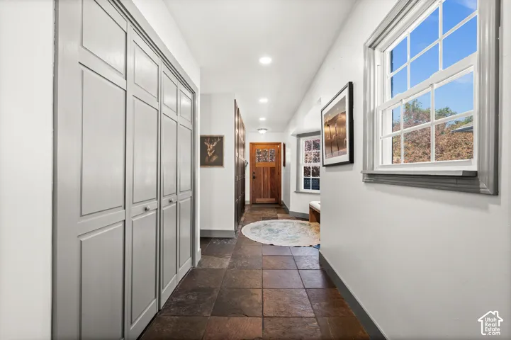 Hallway featuring stone tile flooring, recessed lighting, panel doors, and natural light from a double-hung window