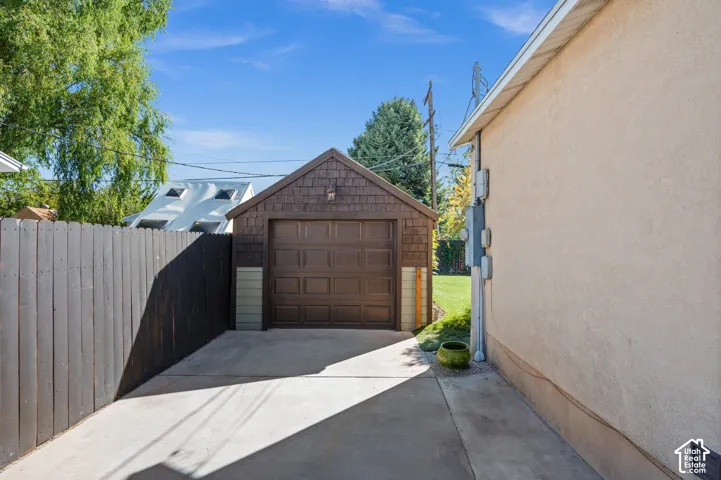 Detached garage with a brown paneled door, shake siding, and concrete driveway