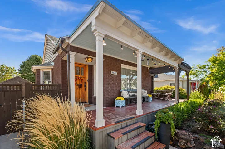 Brick exterior with a covered front porch, an exposed wood pergola, and a private side gate