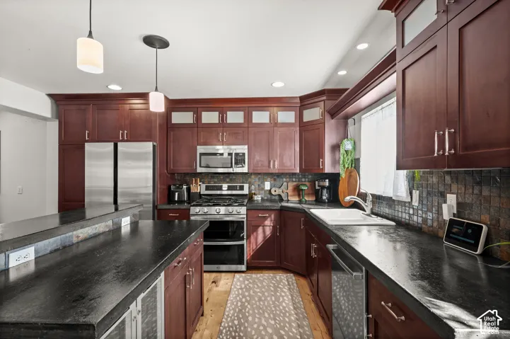 Kitchen featuring wood-finish cabinetry, stainless steel appliances, dark countertops, and a tiled backsplash