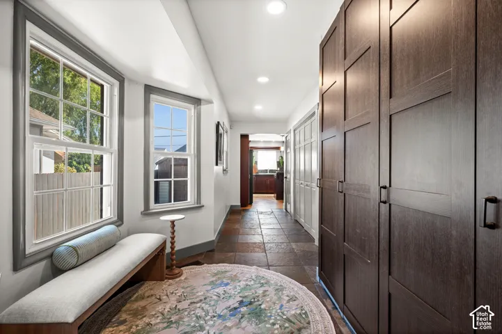 Hallway featuring recessed lighting, multi-pane windows with gray trim, dark wood-finish built-in cabinetry with black hardware, and slate tile flooring