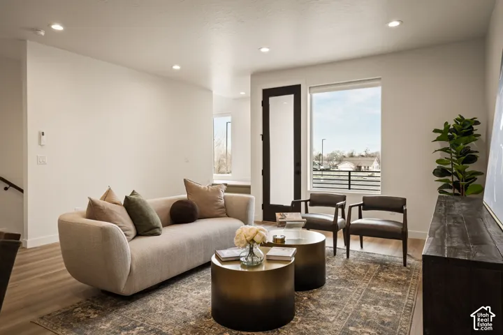 Neutral interior featuring wood-finish flooring, recessed lighting, and a full-height glass-panel door with matte black hardware