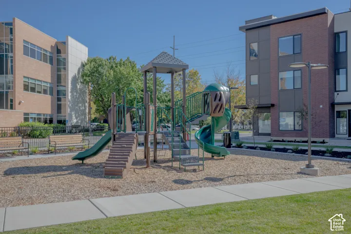 Recreational area featuring a multi-level structure with slides, stairs, and a metal roof, complemented by wood mulch ground cover and permanent metal seating