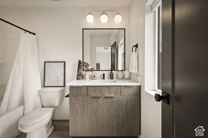 Bathroom vanity featuring wood-finish cabinetry, a white countertop with an integrated basin, a matte black faucet, a framed rectangular mirror, and a three-globe light fixture