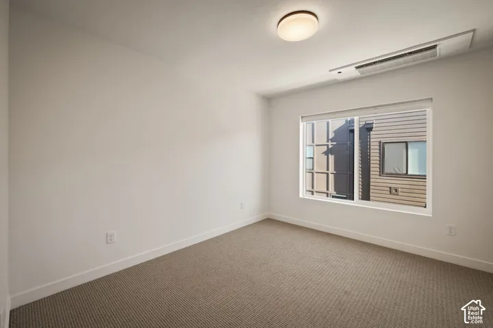Bright secondary bedroom showcasing neutral wall finishes, recessed ceiling lighting, and plush carpet flooring