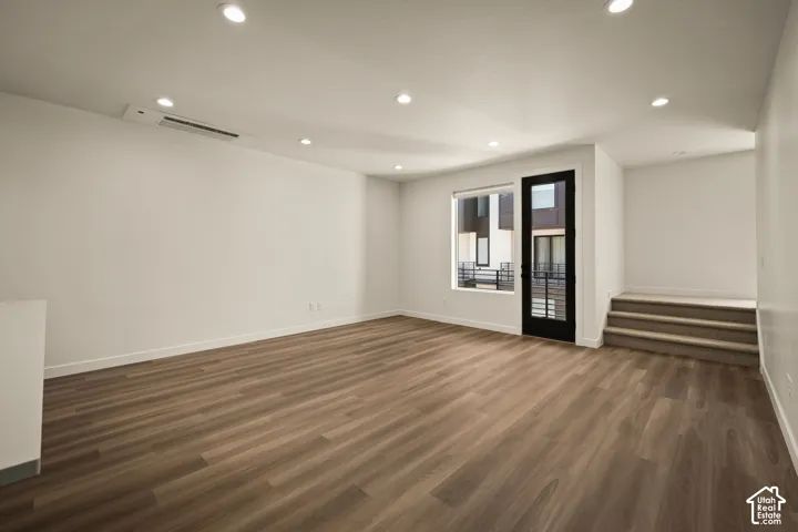 Expansive room featuring wood-finish flooring, recessed lighting, and a white color palette