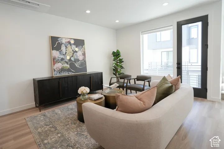 Neutral-toned interior featuring wood-finish flooring, recessed lighting, and a full-height glass-paneled door