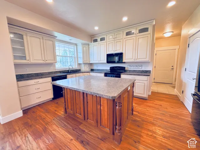 Gourmet kitchen featuring custom cabinetry with glass-front uppers, granite countertops, a substantial center island with wood-finish base throughout the open layout.