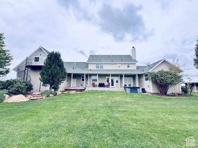 Expansive rear exterior with a manicured lawn, spiral staircase, and full-length deck