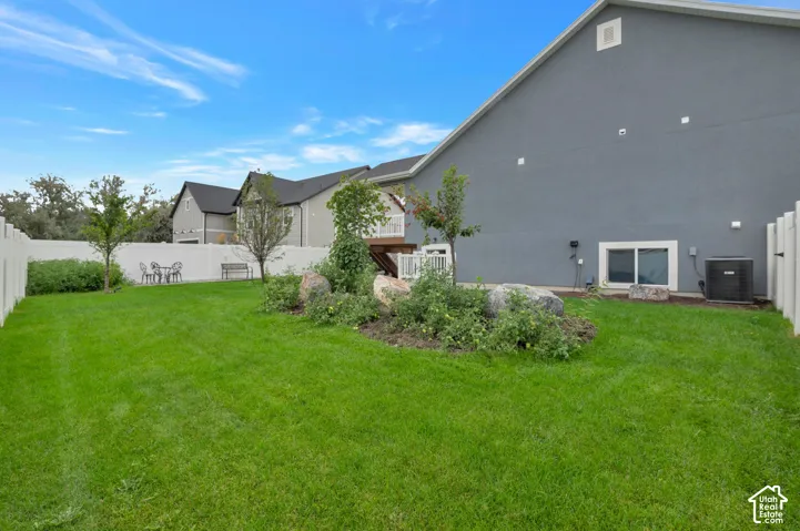 Expansive backyard featuring a manicured lawn, established landscaping, and a white privacy fence