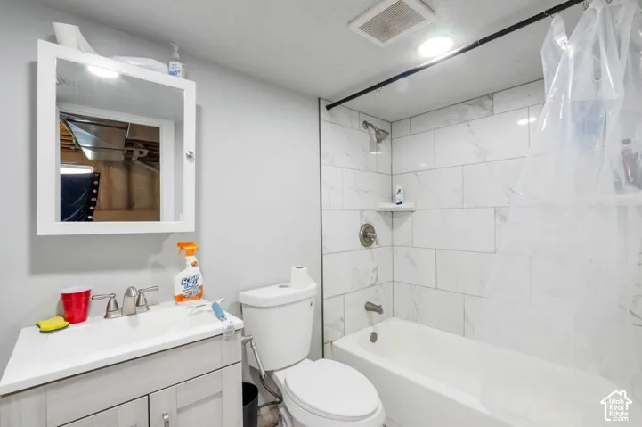 Bathroom featuring a white vanity with integrated sink, wall-mounted medicine cabinet, white toilet, and a bathtub with white subway tile surround