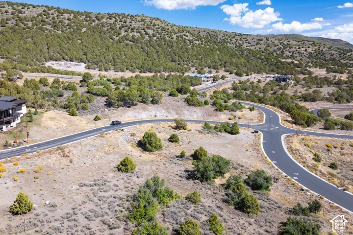 Paved roadways with an intersection, surrounded by extensive natural landscaping and distant mountainous terrain