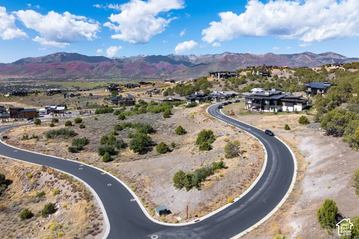 Curved paved roads throughout a residential area, surrounded by natural landscaping, with distant mountain ranges