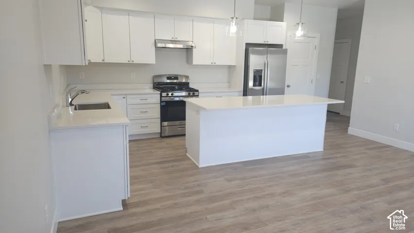 White cabinetry with stainless steel hardware, stainless steel range and refrigerator, quartz countertops, and wood-finish flooring