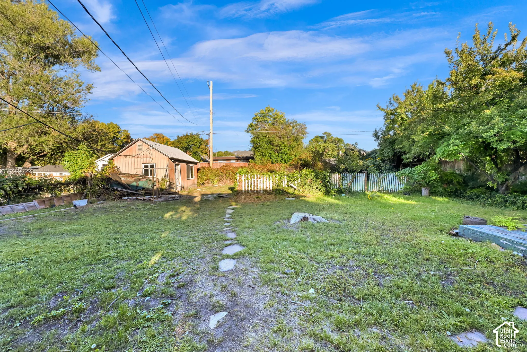 Expansive grassy yard with a stepping stone path leading to a detached structure