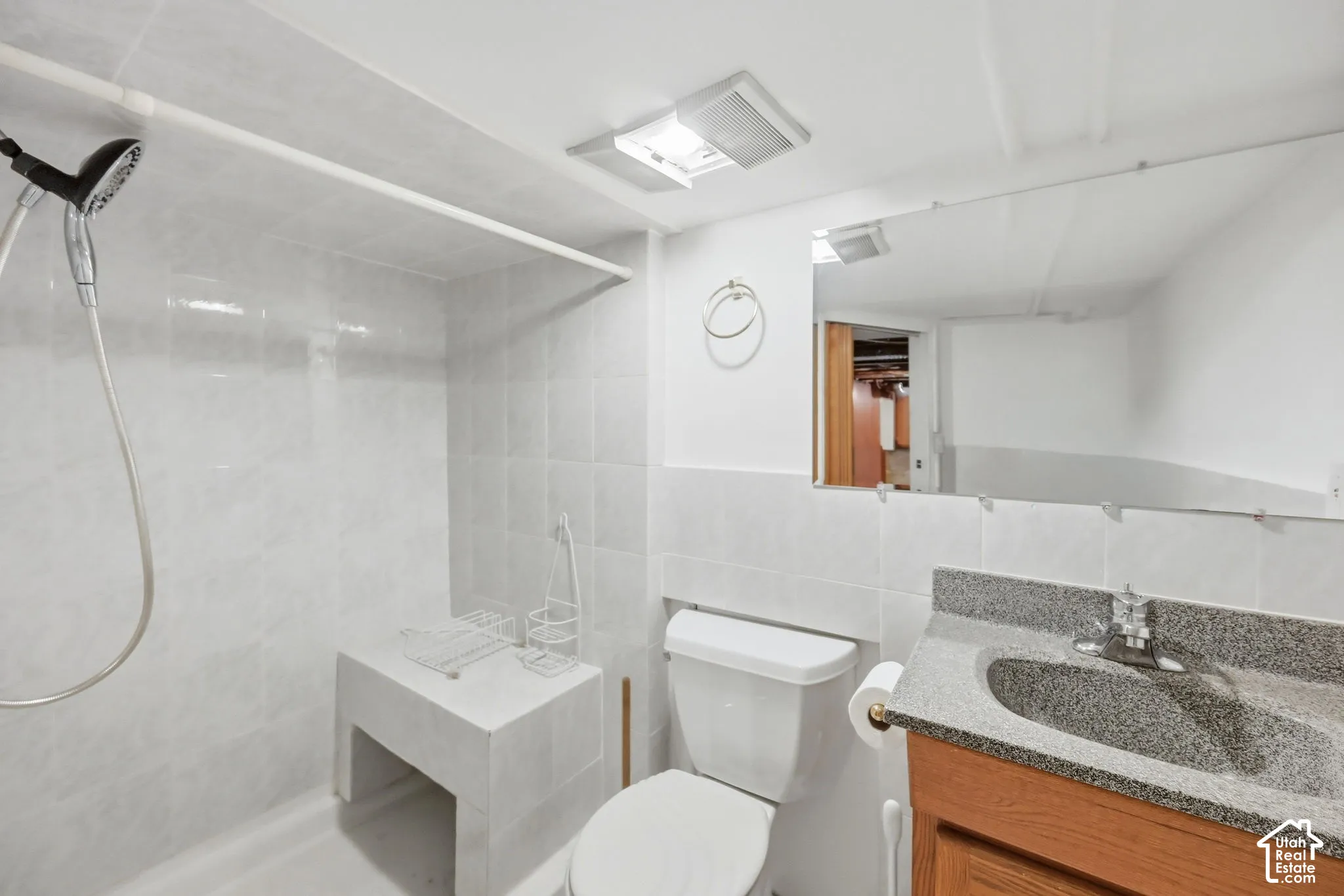 Tiled shower stall with an integrated bench and handheld shower head