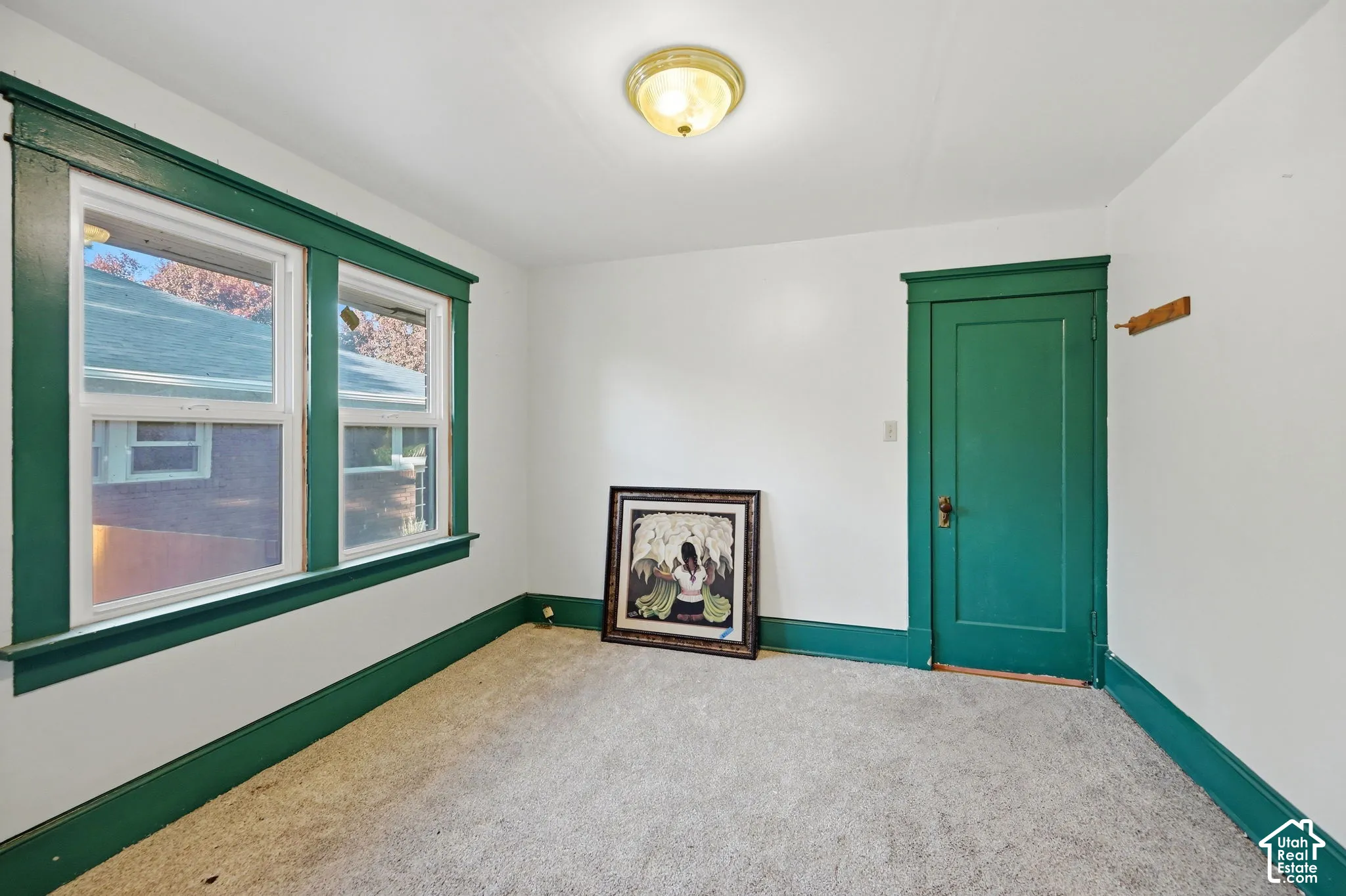 White walls with green trim, carpeted flooring, and a flush mount light fixture