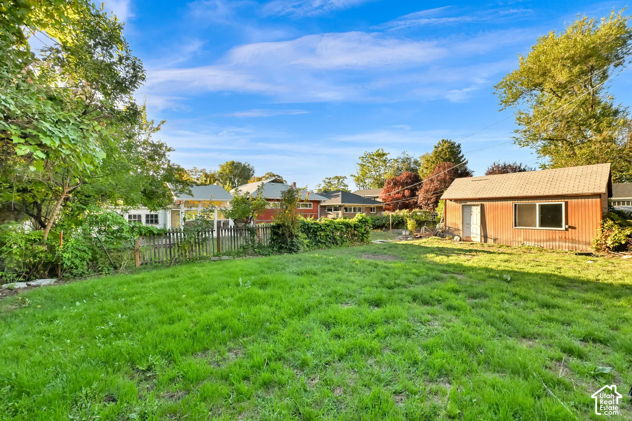 Expansive grassy yard with a detached storage shed and mature perimeter trees
