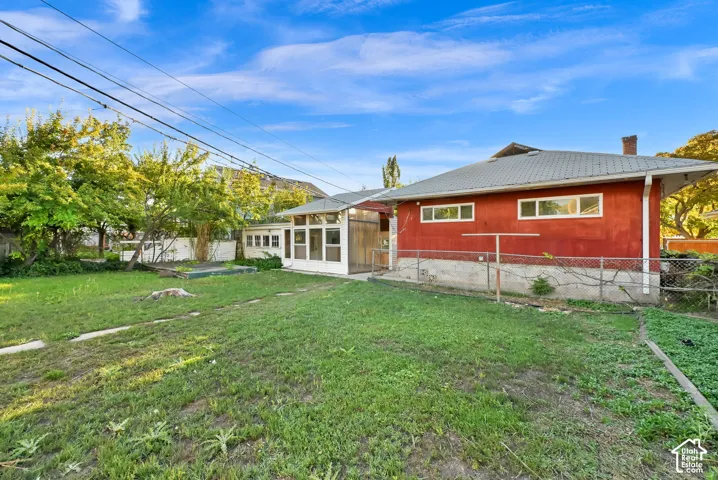 Charming red-exterior home with expansive backyard featuring mature landscaping and established lawn space