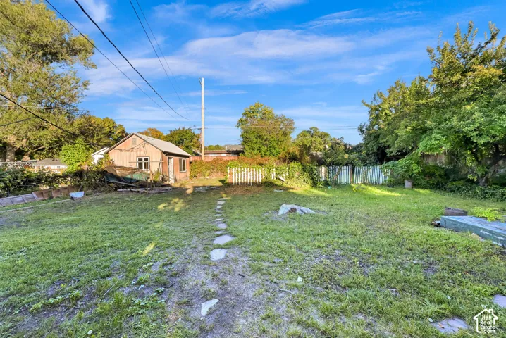 Expansive grassy yard with a stepping stone path leading to a detached structure