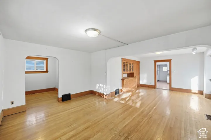 Hardwood flooring, built-in wooden cabinetry, recessed window, and arched doorways