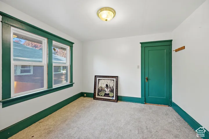 White walls with green trim, carpeted flooring, and a flush mount light fixture