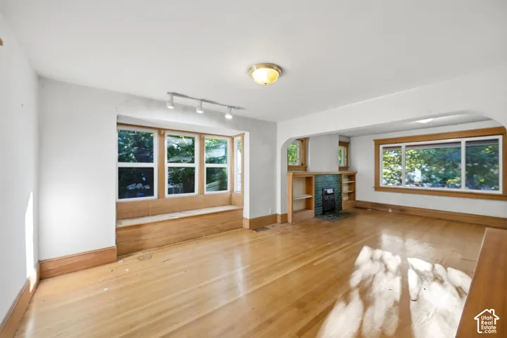 Hardwood flooring throughout, built-in window seating, tiled fireplace with built-in shelving, and multiple large windows