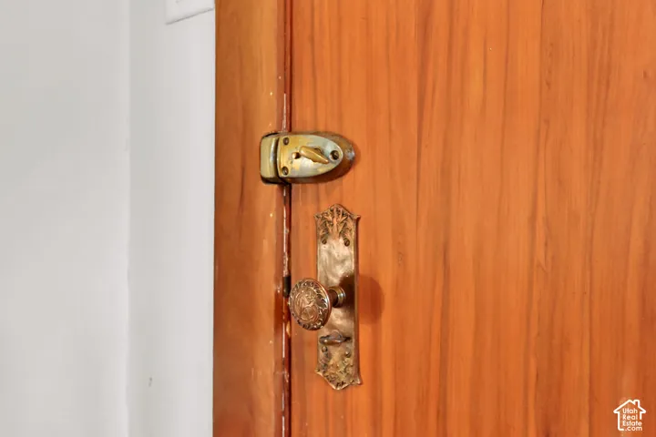 Wood-finish door with a brass-tone door knob, a brass-tone deadbolt, and decorative brass-tone hardware