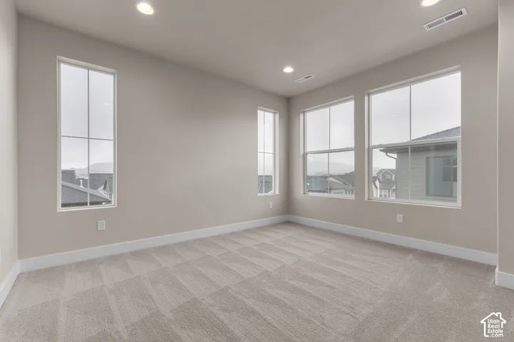 Wall-to-wall patterned carpet, multiple windows with white trim, recessed lighting, and a neutral wall color