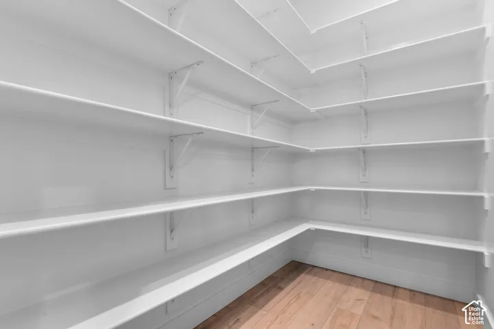 White shelving system, wood-finish flooring, multiple shelving tiers, corner shelving configuration, white walls