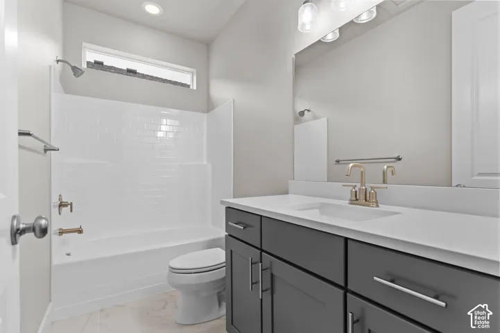 White subway tile bath surround, brushed nickel fixtures, gray shaker cabinetry, engineered stone countertop, and light-colored tile flooring