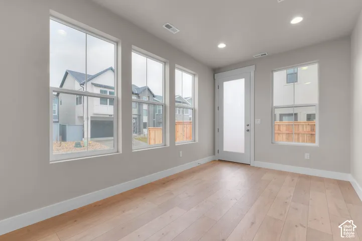 Light wood-finish flooring, recessed ceiling lighting, multiple windows, and a frosted glass door