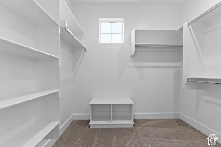 Walk-in closet with extensive shelving, multiple hanging rods, and a built-in storage bench