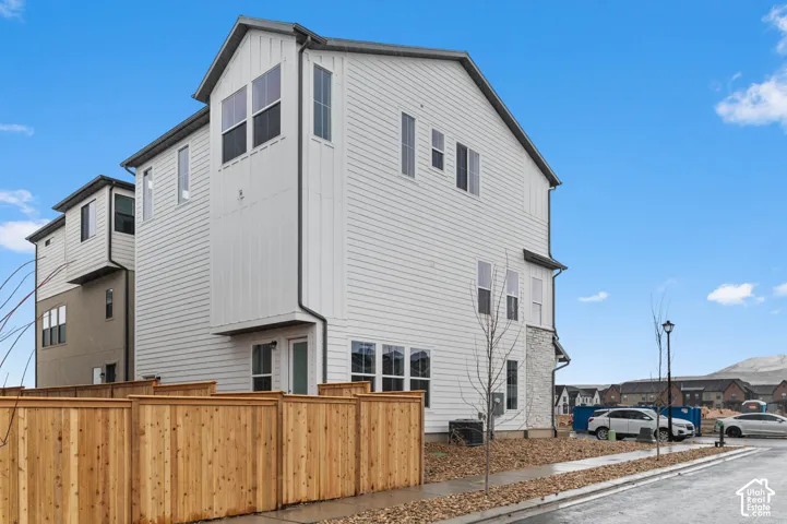 White siding exterior with board and batten accents, a light stone facade, and multiple windows