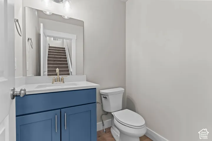 Blue-painted vanity cabinetry with brushed nickel hardware, white countertop with integrated sink, brushed nickel faucet, and a wall-mounted mirror with overhead lighting
