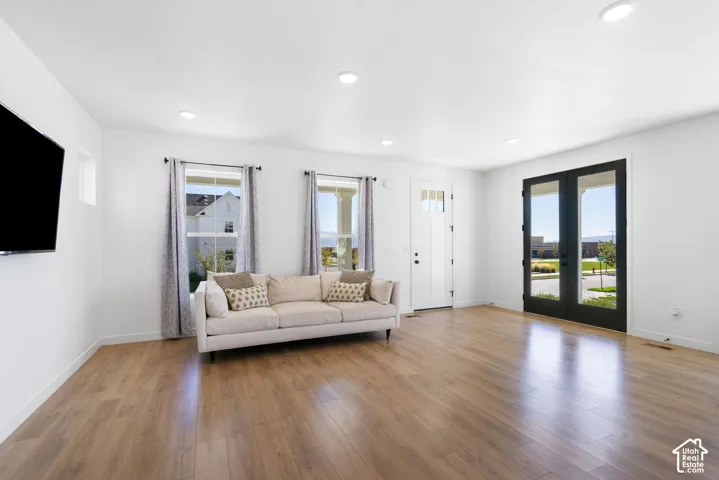 Wood-finish flooring throughout, recessed lighting, and a white front door with upper glass paneling