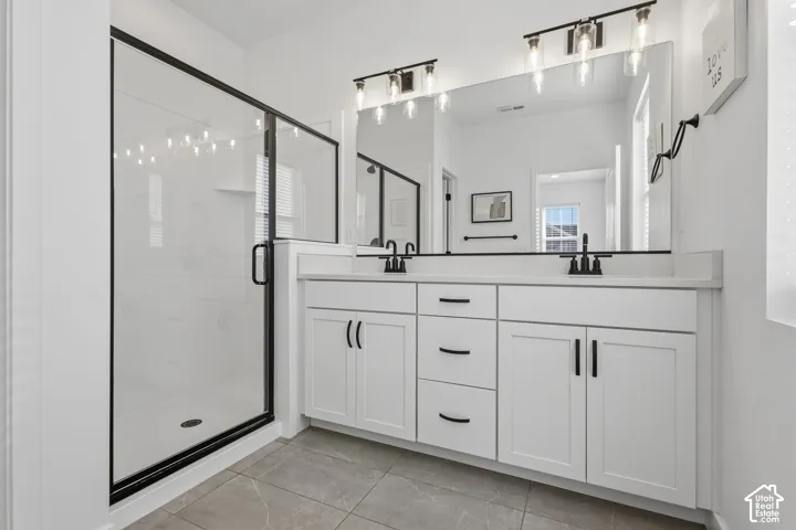Dual vanity with white cabinetry, matte black hardware, and an expansive mirror