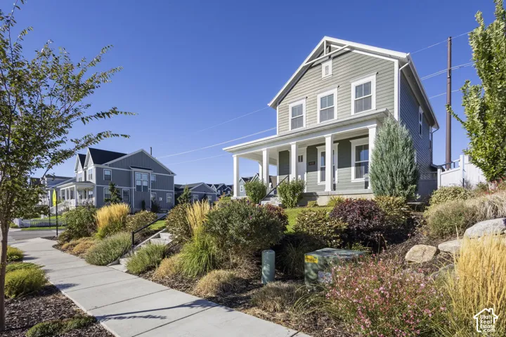 Two-story residence featuring siding exterior, an inviting covered front porch, and mature landscaping