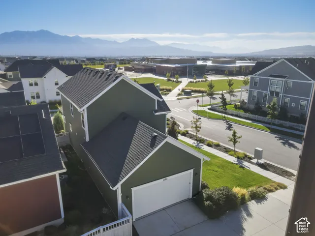 Green exterior with white trim, attached garage, concrete driveway, and asphalt shingle roof