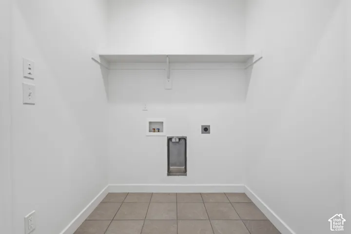 Laundry area featuring tile flooring, a built-in white shelf, and multiple wall outlets