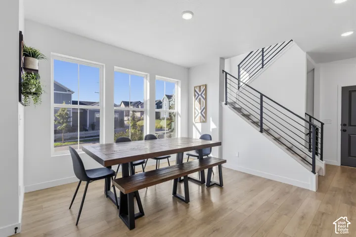 Recessed lighting, wood-finish flooring, white walls, and a staircase with metal railing