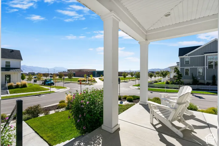 Covered front porch with white columns, concrete flooring, and beadboard ceiling