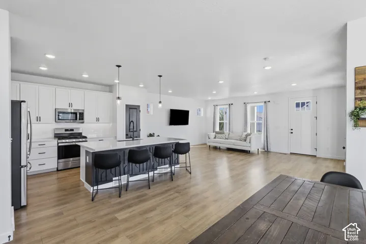 Open-concept living area featuring wood-finish flooring, recessed lighting, and white walls