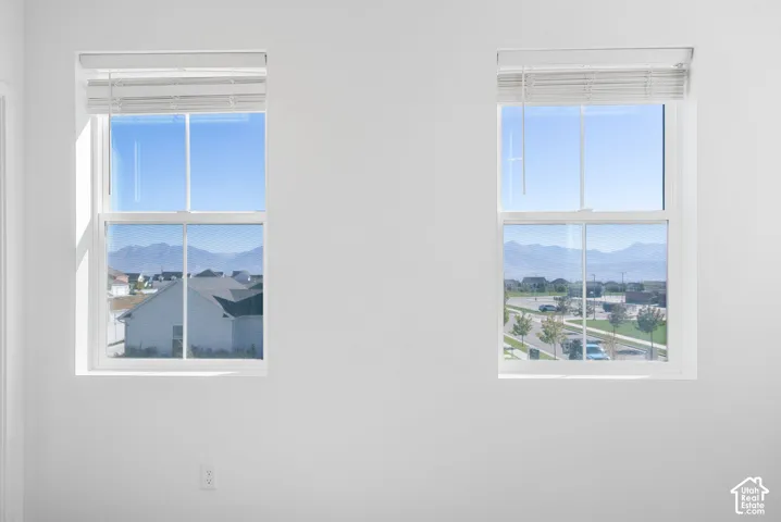 Dual vertical windows with white frames, offering mountain and neighborhood scenery