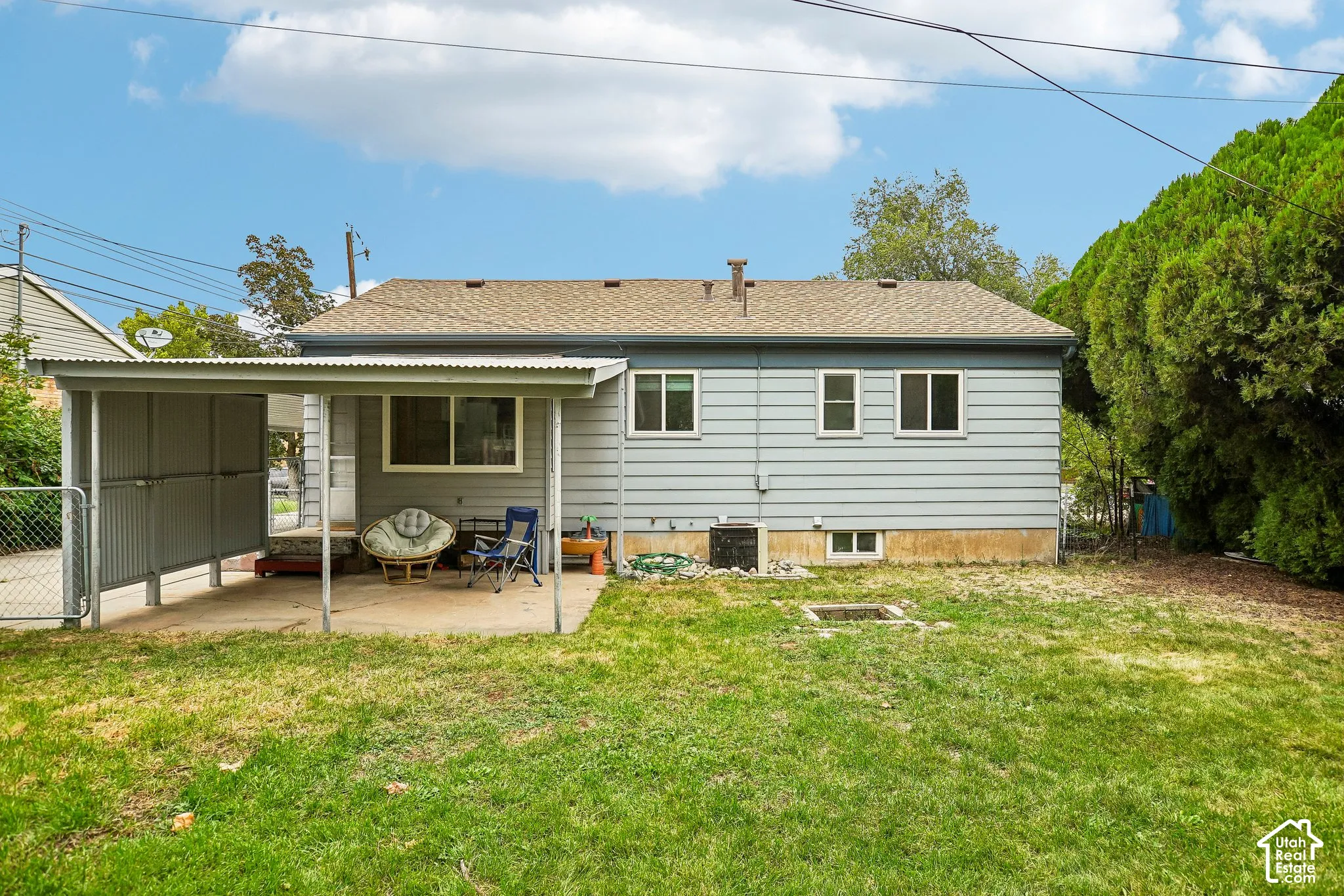 Expansive backyard featuring a manicured lawn, established perimeter trees, and a covered patio with direct access to the residence