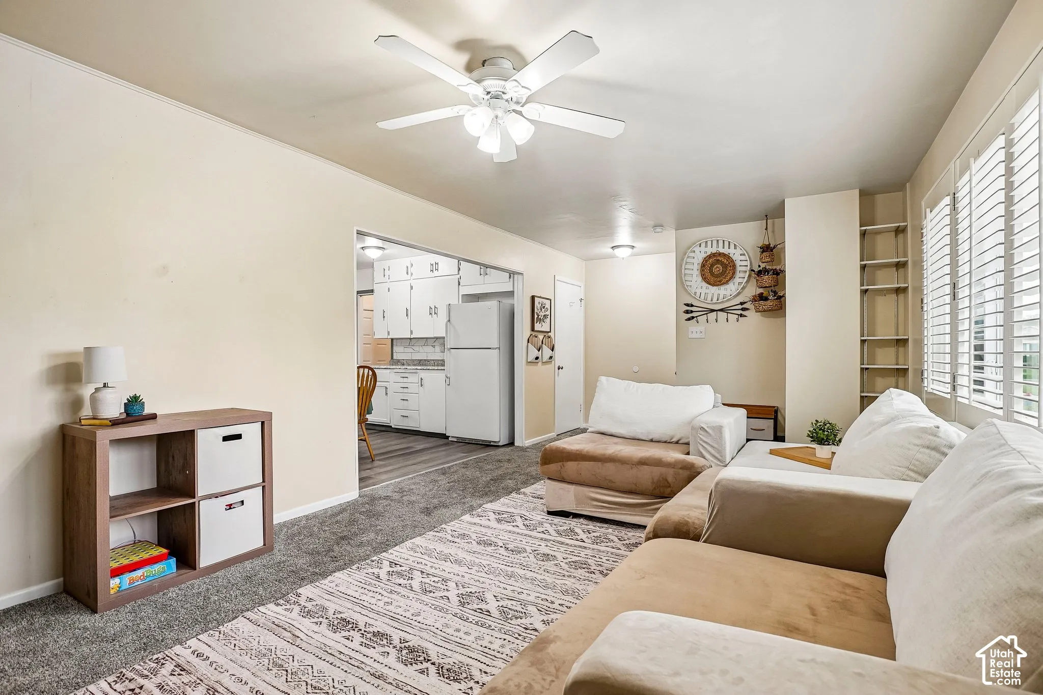 Recessed lighting, ceiling fan, built-in shelving, window shutters, and a pass-through opening to the kitchen