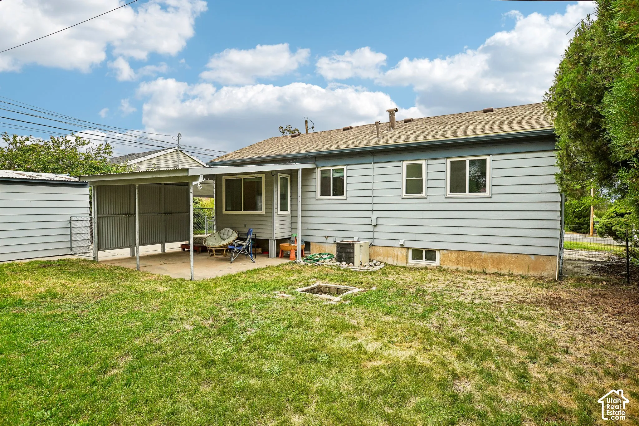 Rear exterior with horizontal siding, multiple windows, an attached covered patio, and a separate storage shed