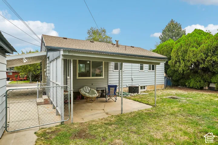 Covered patio with concrete flooring, chain-link fence, and a spacious grassy area