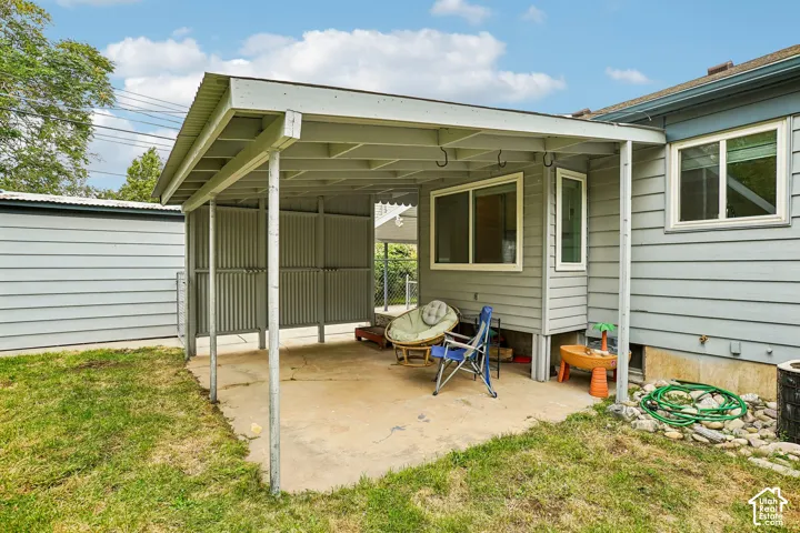 Covered concrete patio with a corrugated metal roof and a detached shed